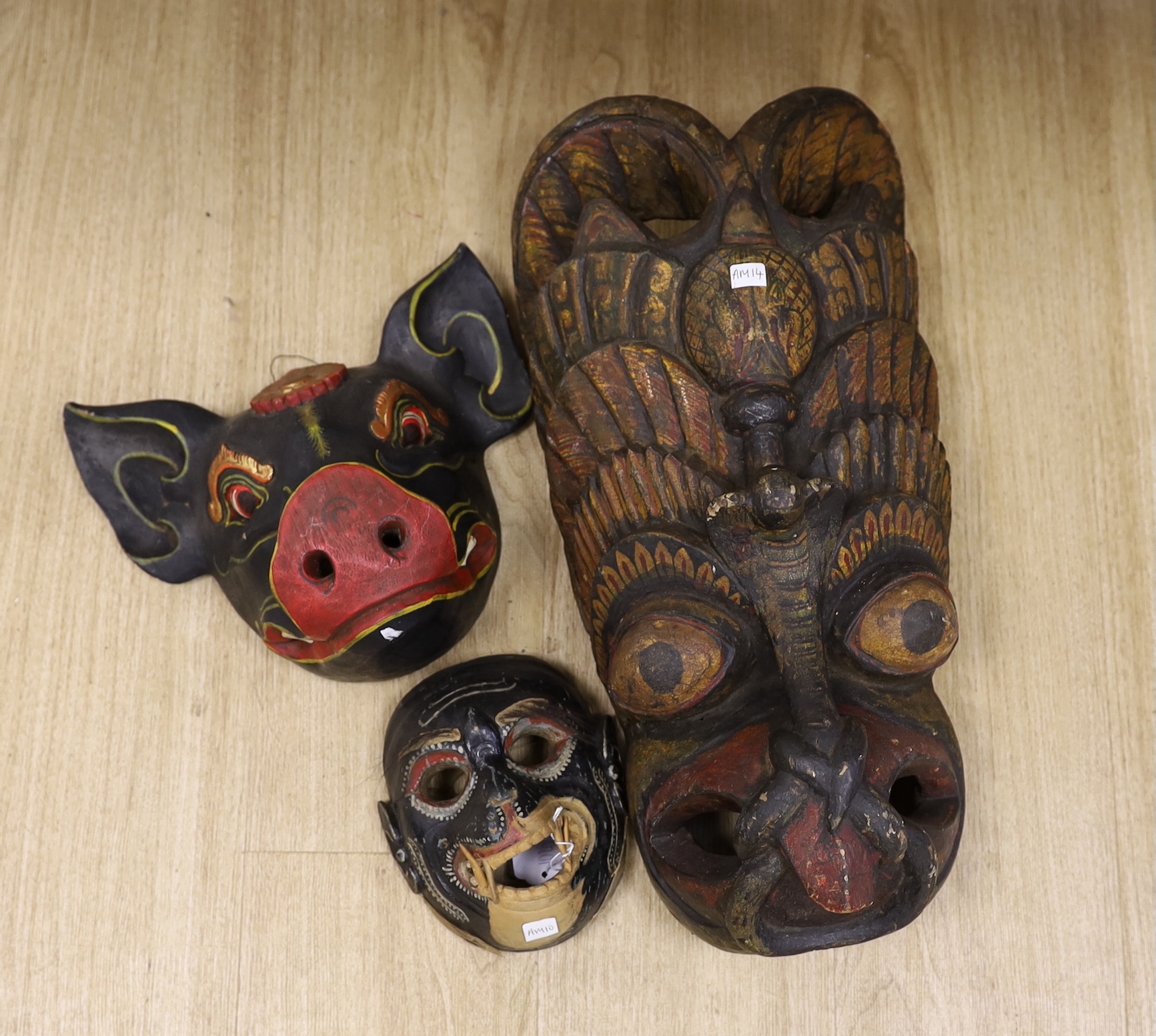 A Ceylonese painted wood mask, an East Java mask and a pig mask, largest 50cm long